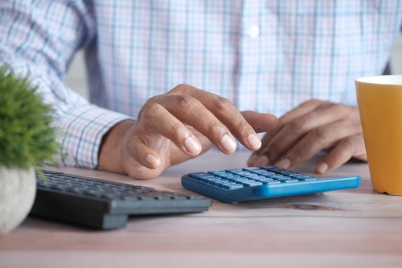 Un homme utilise une calculatrice pour calculer ses frais d'emménagement.